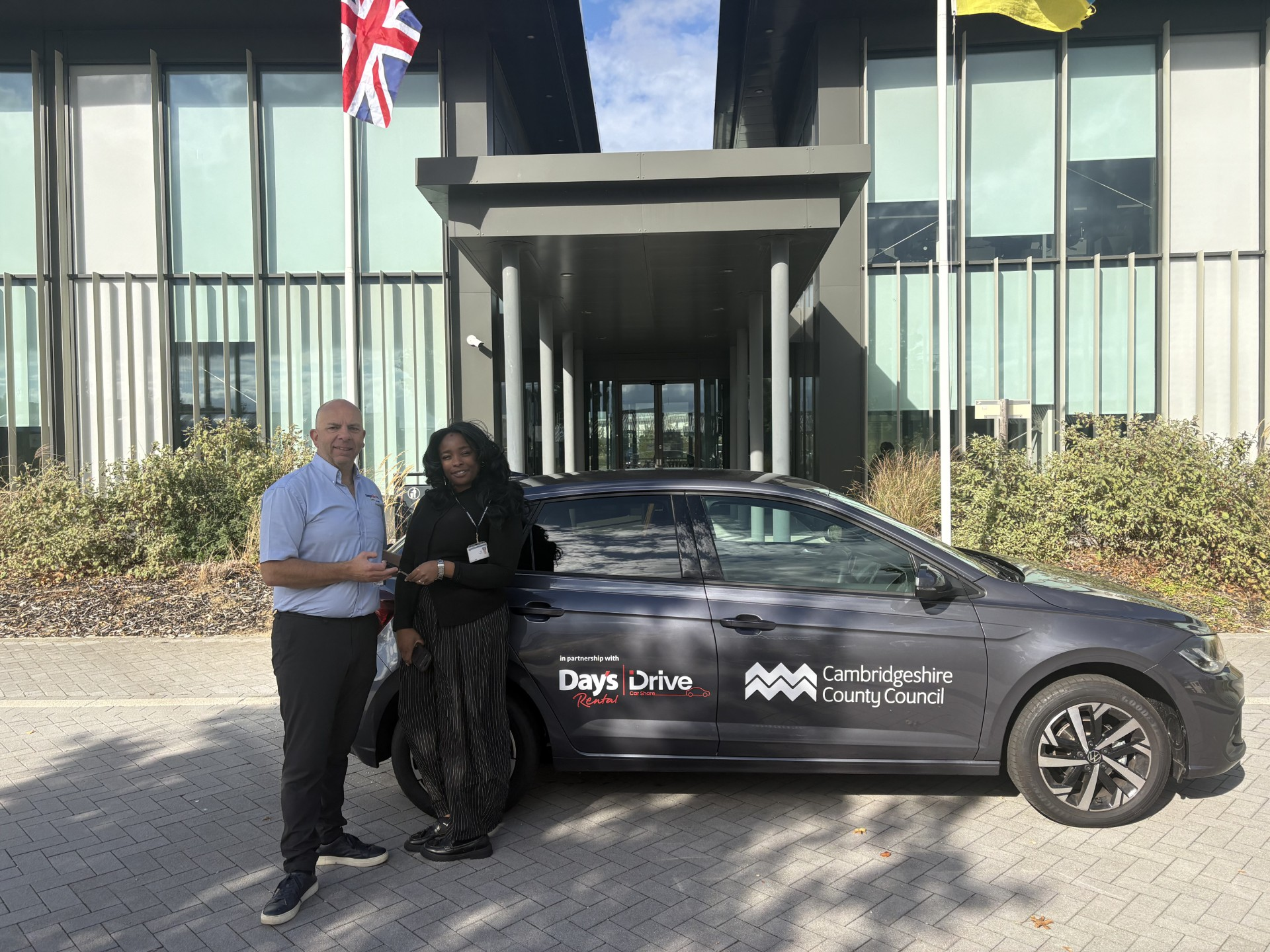 Day’s Rental representative handing vehicle keys to Zeena Weekes beside a car displaying Day’s iDrive and Cambridgeshire County Council branding.