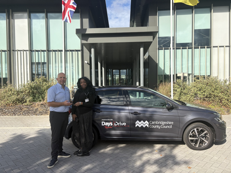 Day’s Rental representative handing vehicle keys to Zeena Weekes beside a car displaying Day’s iDrive and Cambridgeshire County Council branding.